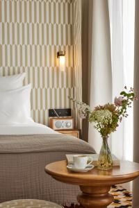 a bedroom with a bed and a table with a vase of flowers at Hôtel Noucha in Paris