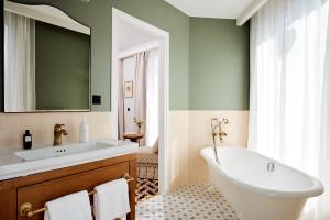 a bathroom with a tub and a sink and a mirror at Hôtel Noucha in Paris