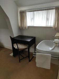 a bathroom with a tub and a sink and a desk at Zit slaapkamer op de 2e etage in een rietgedekte villa met gedeelde douche en keuken in Wassenaar