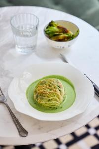 a table with a plate of food and a bowl of broccoli at Hôtel Noucha in Paris