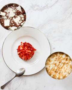 a plate of food with strawberries on a table with two spoons at Hôtel Noucha in Paris