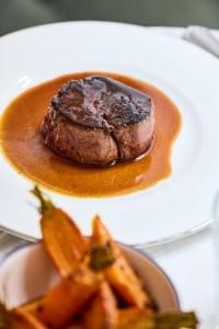 a plate of food with a piece of meat and carrots at Hôtel Noucha in Paris