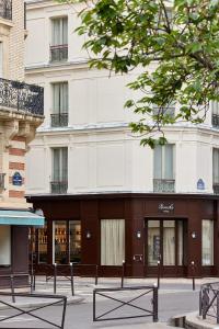 a large white building with benches in front of it at Hôtel Noucha in Paris