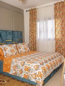 Un dormitorio con una cama con un edredón naranja y blanco. en MAXIM HOUSE, Denver, 24h sur 24 Internet, Electricité, Eau, Canal Sat, Parking Privé, Sécurité,Gardien, en Douala