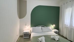 een slaapkamer met een groene muur en een bed met handdoeken bij B&B La Palma in Petacciato +19 foto's