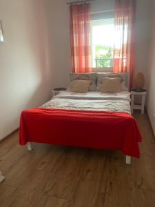 a bedroom with a bed with a red blanket on it at APARTAMENT MARTA in Biłgoraj