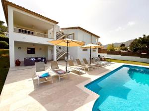 ein Pool mit Stühlen und Sonnenschirmen neben einem Haus in der Unterkunft Villa Gotmar in Port de Pollença