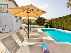 ein Pool mit Stühlen und einem Sonnenschirm neben einem Pool in der Unterkunft Villa Gotmar in Port de Pollença