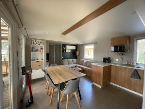 米尼赞海滩KOKUA VACANCES Mobil Homes Résidentiels camping 4 étoiles MIMIZAN PLAGE的配有桌子和沙发的厨房和客厅