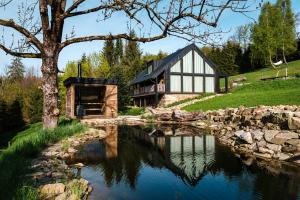 uma casa com um lago na frente em Chata Pytlorka Beskydy offgrid wellness em Zahŭří