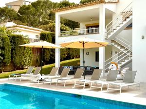 ein Pool mit Stühlen und Sonnenschirmen neben einem Haus in der Unterkunft Villa Gotmar in Port de Pollença