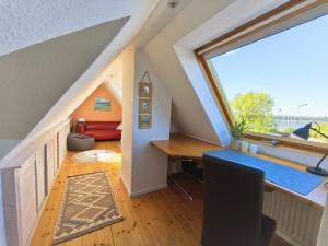 an attic room with a desk and a window at Gold Fehmarn in Fehmarn