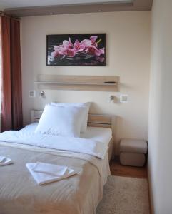 ein Schlafzimmer mit einem großen weißen Bett mit rosa Blumen an der Wand in der Unterkunft Hotel Mis in Salzberg