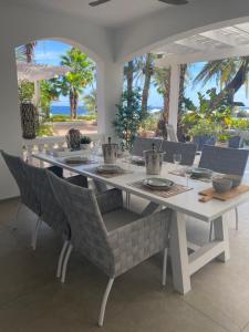 a white dining table and chairs with a view of the ocean at Palms & Pools apartment at Curacao Ocean Resort in Willemstad