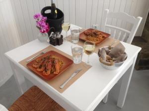 una mesa blanca con dos platos de comida y copas de vino en Laokasti Villas, en Oia