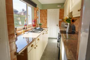 a kitchen with white cabinets and a sink and a window at George Street Beverley in Beverley
