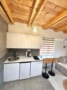 a kitchen with white cabinets and a sink and a table at Lux Montis in Ninkovići +11 photos