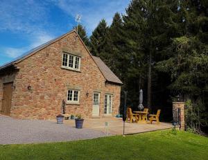 a brick building with a wooden deck with a table at Flurry's Lodge in Coleford
