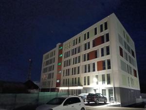 a white building with cars parked in a parking lot at NXN Airportstay in Cluj-Napoca