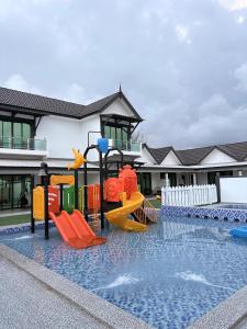 a pool with a playground in front of a building at Eleven25 Roomstay in Dungun