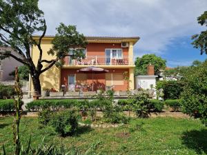 a house with a balcony and an umbrella at APP_garden_1 in Novi Vinodolski