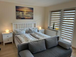 a bedroom with a bed and a couch in a room at Ferienwohnung Ritthoff Perlebucht - mit Strandkorb am Meer und kostenloser Eintritt ins Schwimmbad in Büsum