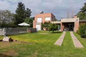 einen Hof mit einem Backsteinhaus mit einem Regenschirm in der Unterkunft Casa El Descanso in Paraná