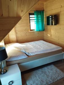 a bed in a log cabin with a window at Bajkowa Chatka in Bodzentyn