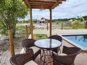 a patio with a table and chairs next to a pool at Taipu House Fantástica com piscina em condomínio in Barra Grande