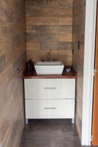 ein Badezimmer mit einem weißen Waschbecken und einer Holzwand in der Unterkunft Casa El Descanso in Paraná