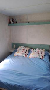 - un lit bleu avec 2 oreillers au-dessus dans l'établissement Le fief, à Le Tablier