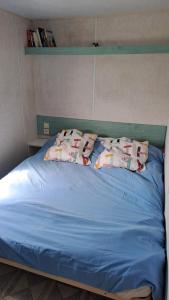 - un lit bleu avec des oreillers au-dessus dans l'établissement Le fief, à Le Tablier