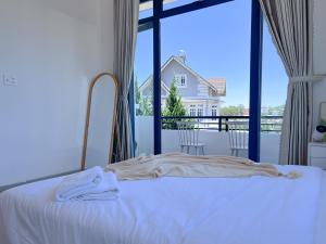 a bedroom with a bed and a large window at Lux Nest Villa Đà Lạt in Da Lat