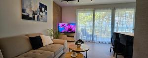 a living room with a couch and a flat screen tv at Pine & Sun Apartment - Hevenia Pogorzelica in Pogorzelica