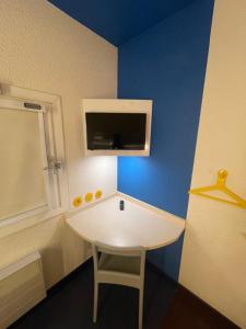 a table in a room with a blue wall at Unisotel Bollène A7 Ex-Hotel F1 in Bollène +11 photos