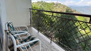 a balcony with two chairs and a view of a mountain at Murree - Bhurban Apartment with Private Balcony in Bhurban