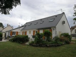 a white house with solar panels on the roof at Maison Du cerf - proche du circuit et du golf des 24H in Mulsanne