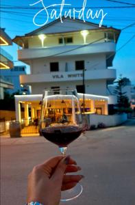a person holding a glass of wine in front of a building at Villa White in Ksamil