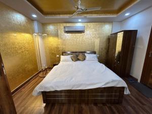 a bedroom with a large bed with white sheets at Shiv - The Luxurious Gold Studio in Jaipur in Jaipur