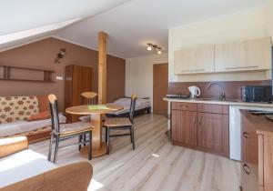 a kitchen and living room with a table and a bed at Willa Helios in Darlowko