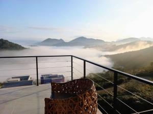 ein Stuhl auf einem Balkon mit Blick auf ein nebliges Tal in der Unterkunft Lux 28 - Casa moderna piscina aquecida e vista in Teresópolis