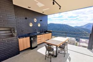 eine Küche mit einem Tisch und Stühlen sowie einen Balkon in der Unterkunft Lux 28 - Casa moderna piscina aquecida e vista in Teresópolis