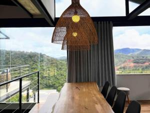 ein Esszimmer mit einem Holztisch und einem großen Fenster in der Unterkunft Lux 28 - Casa moderna piscina aquecida e vista in Teresópolis + 23 Fotos