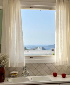 a bathroom with a window and a tub and a sink at At the Side of the Castle in Plaka Milou