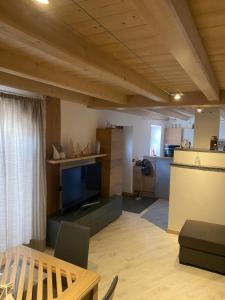 a living room with a flat screen tv and a kitchen at tabià piz meda in Moena