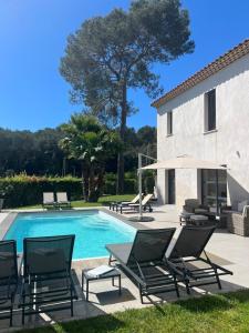 a pool with chaises and chairs next to a house at Villa Les Jasmins - Le Cannet-Vallauris - Modern with AC, ideal for fun and work in Vallauris