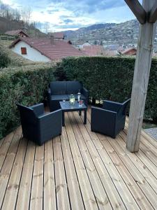 two chairs and a table on a wooden deck at Cocon des chaumes in La Bresse