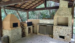 an outdoor kitchen with a stove and a fireplace at Sítio Canto das Águas in Petrópolis