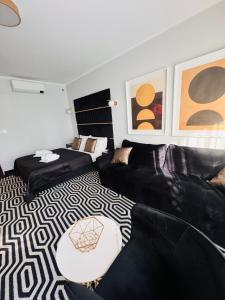 a living room with black leather furniture and paintings at Apartament Solny Resort A032 z klimatyzacją i ogrodem in Kołobrzeg +37 photos