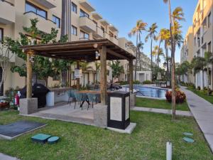 a gazebo with a table and chairs next to a pool at New Oceanfront Apartment in Mazatlán